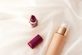 Beige tonal cream bottle make-up fluid foundation base and dark lipstick on silk background, cosmetics products as luxury beauty