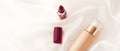 Beige tonal cream bottle make-up fluid foundation base and dark lipstick on silk background, cosmetics products as luxury beauty
