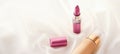 Beige tonal cream bottle make-up fluid foundation base and pink lipstick on silk background, cosmetics products as luxury beauty