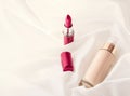 Beige tonal cream bottle make-up fluid foundation base and red lipstick on silk background, cosmetics products as luxury beauty