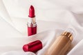 Beige tonal cream bottle make-up fluid foundation base and red lipstick on silk background, cosmetics products as luxury beauty