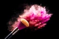 Cosmetic brush with pink and red powder splashes on a black background