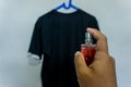 cosmetic concept. man hand holding parfume bottle and spraying to a tshirt. applying perfume to shirt Royalty Free Stock Photo