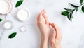 Cosmetic cream on female hands, jars with milk swirl cream and green leaves on white marble table. Flat lay, top view. Woman Royalty Free Stock Photo