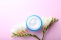 Cosmetic cream and flower on pink background