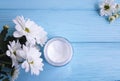 Cosmetic moisturizer mask frame essence product in a glass jar white flowers blue wooden background Royalty Free Stock Photo