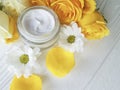 Cosmetic cream, glass yellow rose revitalize on a table white wooden background
