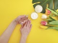 Cosmetic cream, hands manicure essence monstera leaf on yellow colored paper Royalty Free Stock Photo