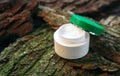 Cosmetic cream jar on tree bark piece side view. Organic cosmetology botanical concept. White plastic container with natural