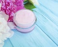 Cosmetic cream, peony flower moisturizer lotion on a blue wooden background Royalty Free Stock Photo