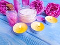 Cosmetic cream, pink rose extract on wooden background, candle