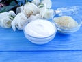 cosmetic cream, rose flower, treatment salt on a blue wooden background