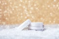 Cosmetic cream in white jar for face and hand skin care. Golden bokeh background. Winter skincare concept