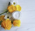 Cosmetic cream, glass yellow rose product face care revitalize on a table white wooden background