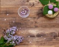 Cosmetic flat lay with a bouquet flowers lilac.Spa handmade raging bombs and hydrogel balls on wooden slice on brown wooden backg Royalty Free Stock Photo