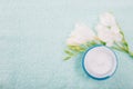 Cosmetic hygienic cream with gentle flowers on light towel background. Skincare product