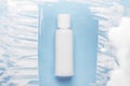 Cosmetic lotion bottle mockup on blue background with foamy smears. Face washing mousse top view. Moisturizing body