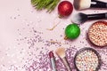 Cosmetic makeup brushes, blush powder, christmas balls, lipstick, holographic glitter confetti in the form of stars on pink Royalty Free Stock Photo