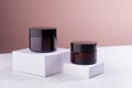 Cosmetic mockup - jars for cream of amber glass with black caps on white podiums. Template for branding identity for cosmetics.