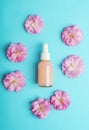 Cosmetic pink serum bottle and sakura blossom on blue background. Natural cosmetics concept. Top view, flat lay, mockup