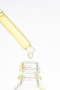 Cosmetic pipette with yellow oily drop close up on white background. Beauty drop of luxurious gold oil or oily serum Royalty Free Stock Photo
