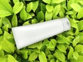 Cosmetic plastic tube on green leaf background. top view Royalty Free Stock Photo