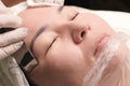 Close up. Asian middle-aged woman lies in the medical office of a beauty salon. Cosmetic procedure for cleaning the face with an e Royalty Free Stock Photo