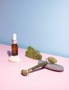 Cosmetic product in a glass bottle with a pipette and gua sha e scraper and roller. Smooth stones nearby. The concept of skin care