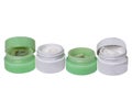 Cosmetic products. Close-up of four opened green and white plastic jars with face cream isolated on a white background.