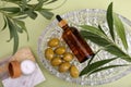 Cosmetic products, olives and leaves on green background, flat lay Royalty Free Stock Photo