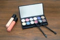 Cosmetic set with eye shadows and brushes in black plastic case with mirror on wooden background Royalty Free Stock Photo