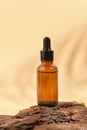 Cosmetic skin care product on tree bark. Natural cosmetics concept. Glass brown serum bottle on beige background with shadows Royalty Free Stock Photo