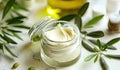 Cosmetic skin cream on a white table surrounded by fresh green leaves and olive oil Royalty Free Stock Photo