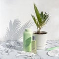 Cosmetic skincare products on marble background with palm leaves shadow. Glass bottle of natural oil, modern concept of organic