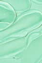 cosmetic smears cream texture on green background. Beauty serum drop. Transparent and creamy skin care product sample