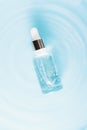 Cosmetic spa medical skincare, glass serum bottle with collagen on blue water background with waves. medical product adverticement