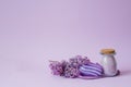 Cosmetic spa set for body care. Sea salt in glass jar, organic soap, washcloth glove and lilac flowers on purple background with Royalty Free Stock Photo