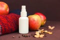 Cosmetic spray bottle, autumn apples, sweater and dry hydrangea flowers on dark brown background. Hair natural oil, body mist, Royalty Free Stock Photo