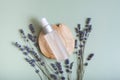 Cosmetic spray bottle on wooden slice top view, flat lay on colored background with lavender flowers. SPA concept