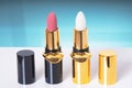 Cosmetic tools. Macro photograph of two opened elegant gold red and white lipsticks on a bright table against abstract light blue Royalty Free Stock Photo