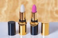 Cosmetic tools. Macro photograph of two opened elegant gold red and white lipsticks on a bright table against abstract light gold Royalty Free Stock Photo