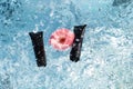 cosmetic tubes of black color in splashes and drops of water on a blue water surface and a beautiful rose flower Royalty Free Stock Photo