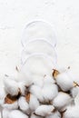 Cosmetic cotton sponges set in bag on white background with dried cotton flowers. Natural makeup remove pad