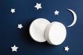 Cosmetic white container on night sky background top view. Skincare cosmetology product, night care concept. Organic cosmetics.