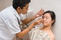 Cosmetician brushing face of Asian girl