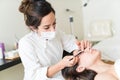 Cosmetician Brushing Hispanic Customer`s Eyelash