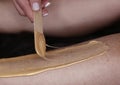 cosmetician hands make depilation procedure on woman legs with wax