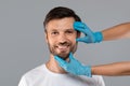 Cosmetician hands in protective gloves touching smiling man face