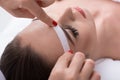 Cosmetician undergoing waxing procedure for human brow