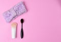 Cosmetics and accessories on a pink background. Black makeup brush, foundation and purple headband on a pink background. flat lay